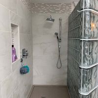Solid surface shower pan with a custom drain location in a glass block shower project - Innovate Building Solutions