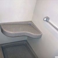 Extended curved bench seat in a solid surface shower system