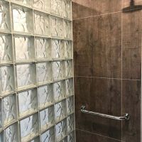 24 inch by 24 inch wood look laminate shower panels with a wave pattern glass block shower wall - Innovate Building Solutions