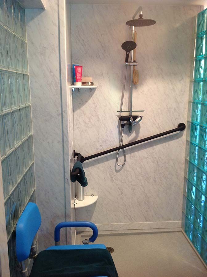 Marble pattern PVC composite wall panels in a light blue glass block shower - Innovate Building Solutions
