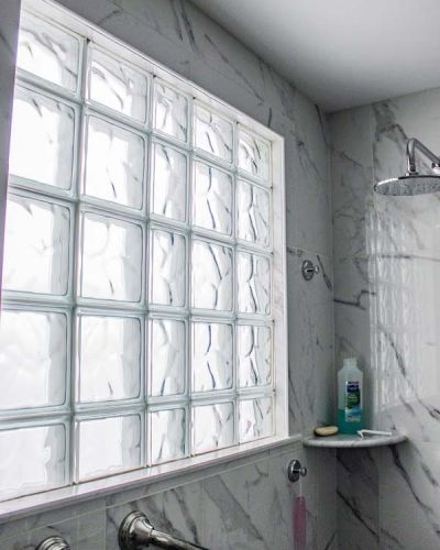 Glass block shower window capped with marble tiles using a wave pattern - Innovate Building Solutions