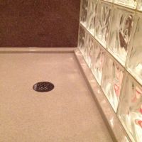 Solid surface shower base with a round drain and wave pattern wall - Innovate Building Solutions