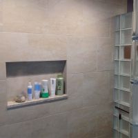 Horizontal tile niche with a granite shelf in a frosted glass block shower wall - Innovate Building Solutions