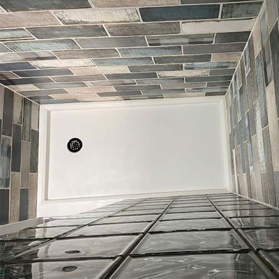 Round drain in a solid surface glass block shower base top down view - Innovate Building Solutions 