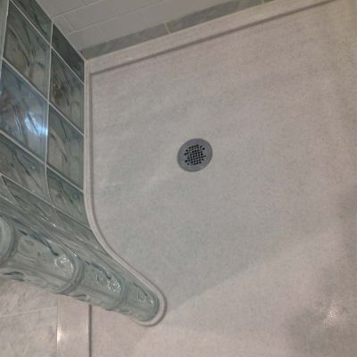 Round drain with a curved glass block wall and a presloped glass block shower pan - Innovate Building Solutions 