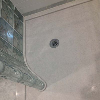 Round drain with a curved glass block wall and a presloped glass block shower pan - Innovate Building Solutions