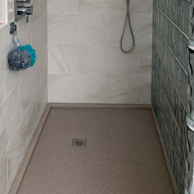 Square drain in a cultured granite shower pan in a gray color - Innovate Building Solutions