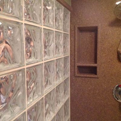Extra tall recessed niche in a glass block shower with solid surface walls by Innovate Building Solutions