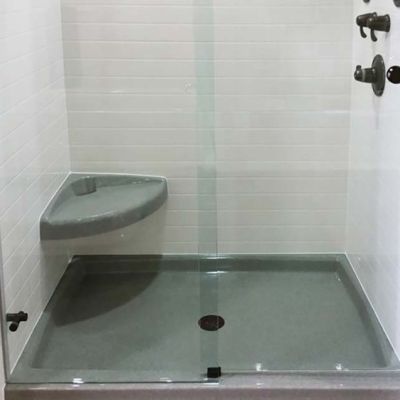 Curved corner seat in a solid surface shower with a pivoting shower door - Innovate Building Solutions